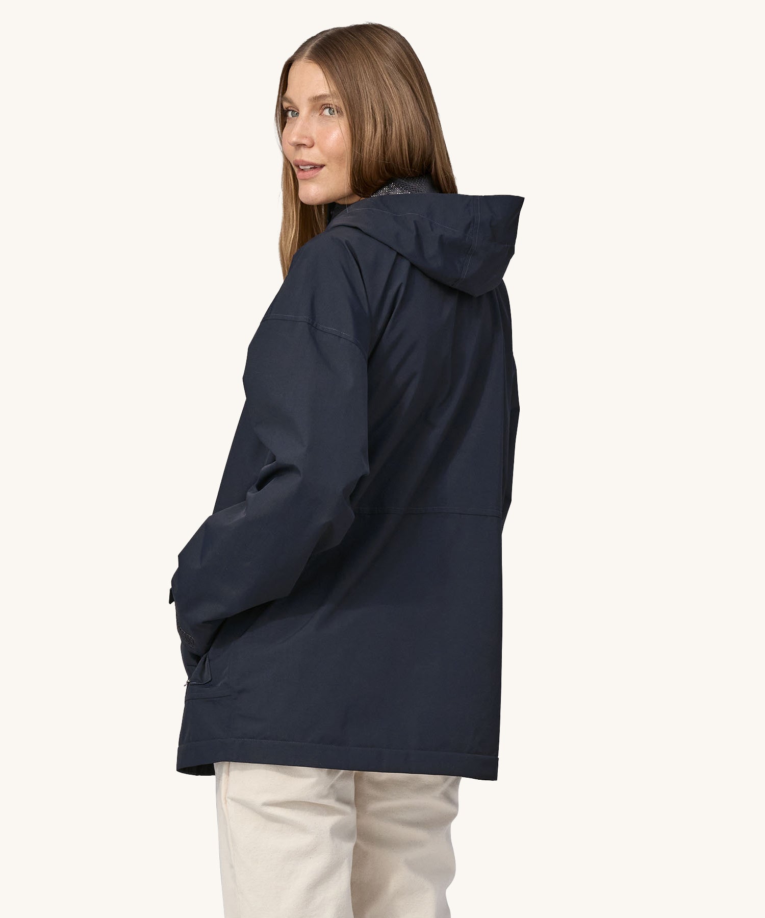 A woman wearing a Patagonia Women's Outdoor Everyday Rain Jacket in a Pitch Blue colour. The woman is facing away from the camera showing the back of the jacket. 