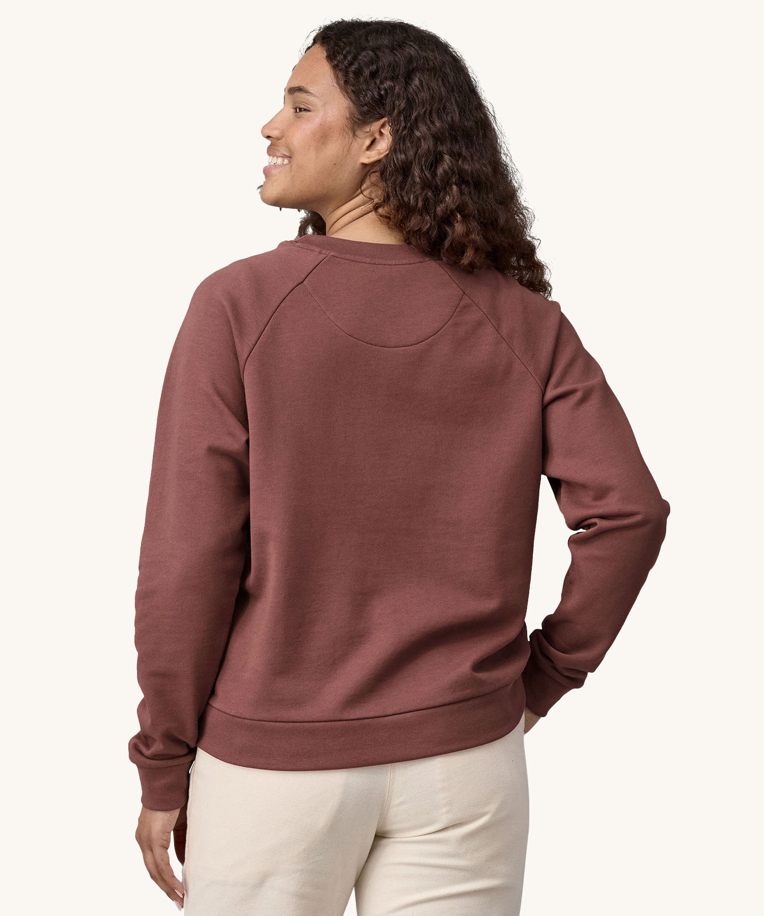 A woman wearing the Patagonia Women's Regenerative Cotton Essential Top in a Dulse Mauve colour. the woman is facing away from the camera showing the back of the top. 