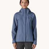 A woman wearing the Patagonia Women's Torrentshell 3L Rain Jacket in a Current Blue colour. We have a wide range of Patagonia adult's and children's coats and clothing at Babipur.