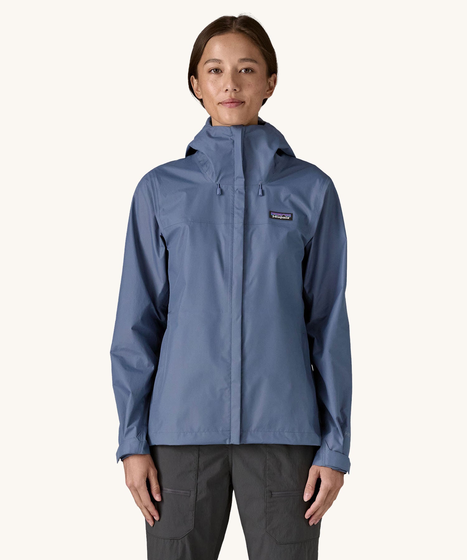 A woman wearing the Patagonia Women's Torrentshell 3L Rain Jacket in a Current Blue colour. We have a wide range of Patagonia adult's and children's coats and clothing at Babipur.