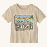 The Patagonia Little Kids Regenerative Fitz Roy Skies T-Shirt in a Undyed Natural colour way on a plain background. 