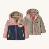 Patagonia little kids tribbles hoody. A reversible coat showing a pink and navy hooded coat and natural fleece alternative side. Features a small chest pocket and side pockets
