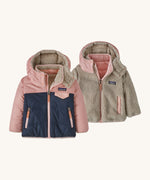 Patagonia little kids tribbles hoody. A reversible coat showing a pink and navy hooded coat and natural fleece alternative side. Features a small chest pocket and side pockets