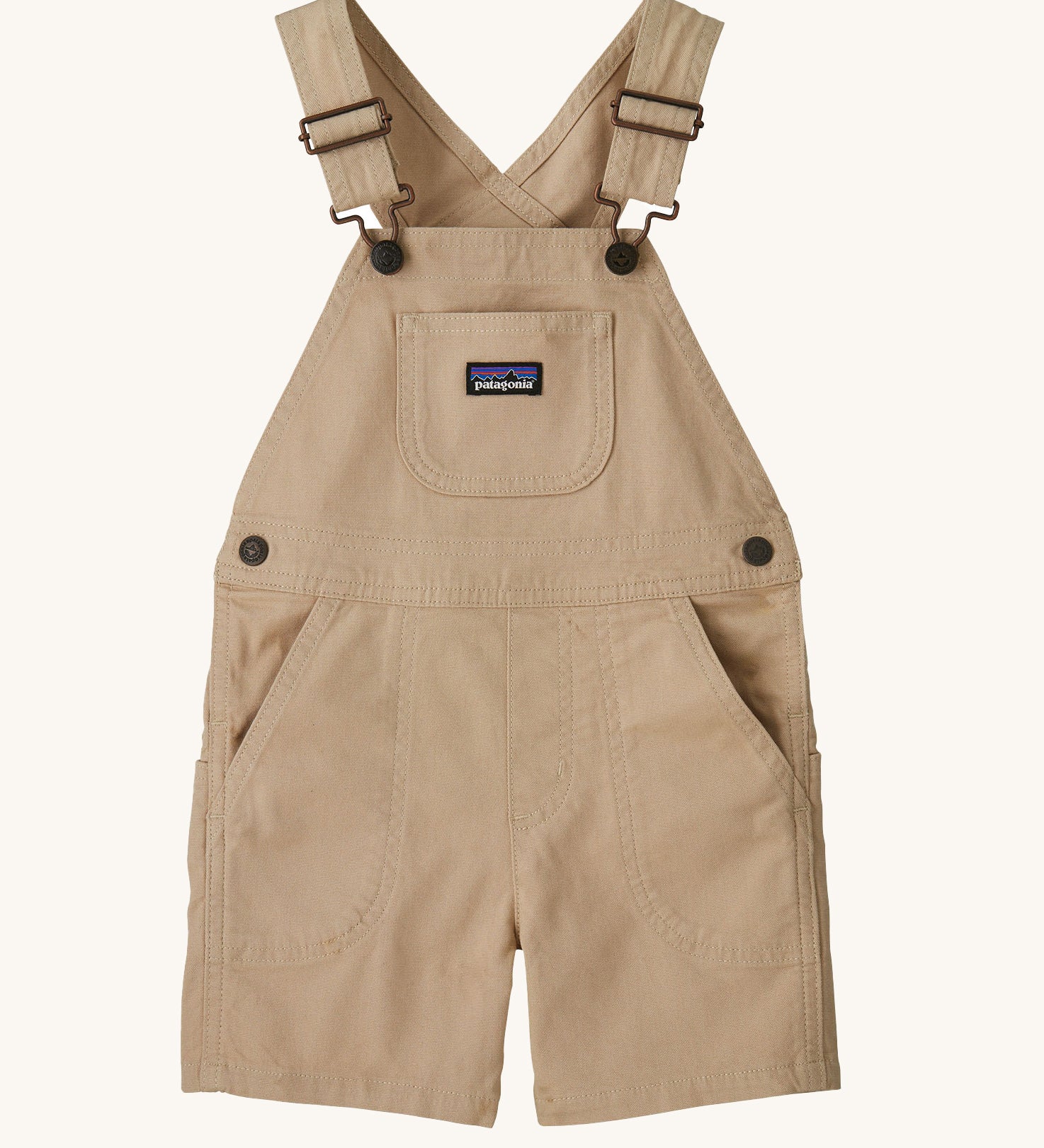 The Patagonia Little Kids Stand Up Shortalls in an Oar Tan colour on a plain background.