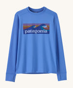 Patagonia kids long sleeve tshirt in a light blue colour with logo on a cream background.