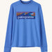 Patagonia kids long sleeve tshirt in a light blue colour with logo on a cream background.