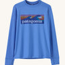 Patagonia kids long sleeve tshirt in a light blue colour with logo on a cream background.