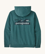 Patagonia men's uprisal hoodie in turquoise with boarshort logo on the back on cream background.
