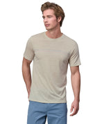 Man wearing a Patagonia men's Capilene Cool merino blend shirt in a cream colour.