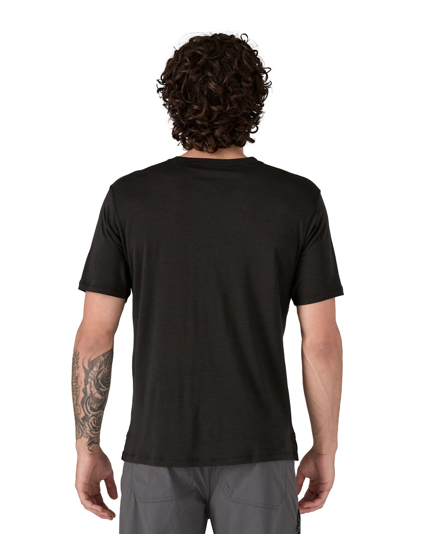 Man wearing a Patagonia men's Capilene merino blend black short sleeved t-shirt with a loose fit facing away.