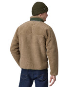 A man wearing a Patagonia Men's Classic Retro-X Jacket in a Seabird Grey colour and a green beanie hat facing away from the camera showing the back of the jacket. 