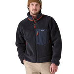A man wearing a Patagonia Men's Classic Retro-X Jacket in a dark smolder blue colour.  