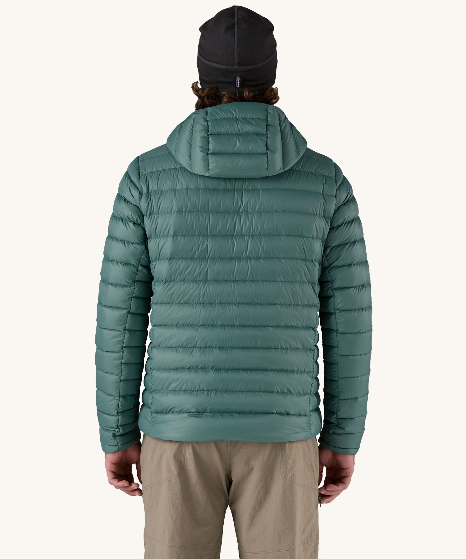 A man wearing the Patagonia Men's Down Sweater Hoody Jacket in a Wetland Blue colour. He is facing away from the camera showing the back of the jacket. 