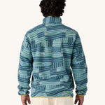 A man wearing the Patagonia Men's Lightweight Synchilla Snap-T Fleece in Quilty Fitz / Wetland Blue. He is facing away from the camera showing the back of the top. 