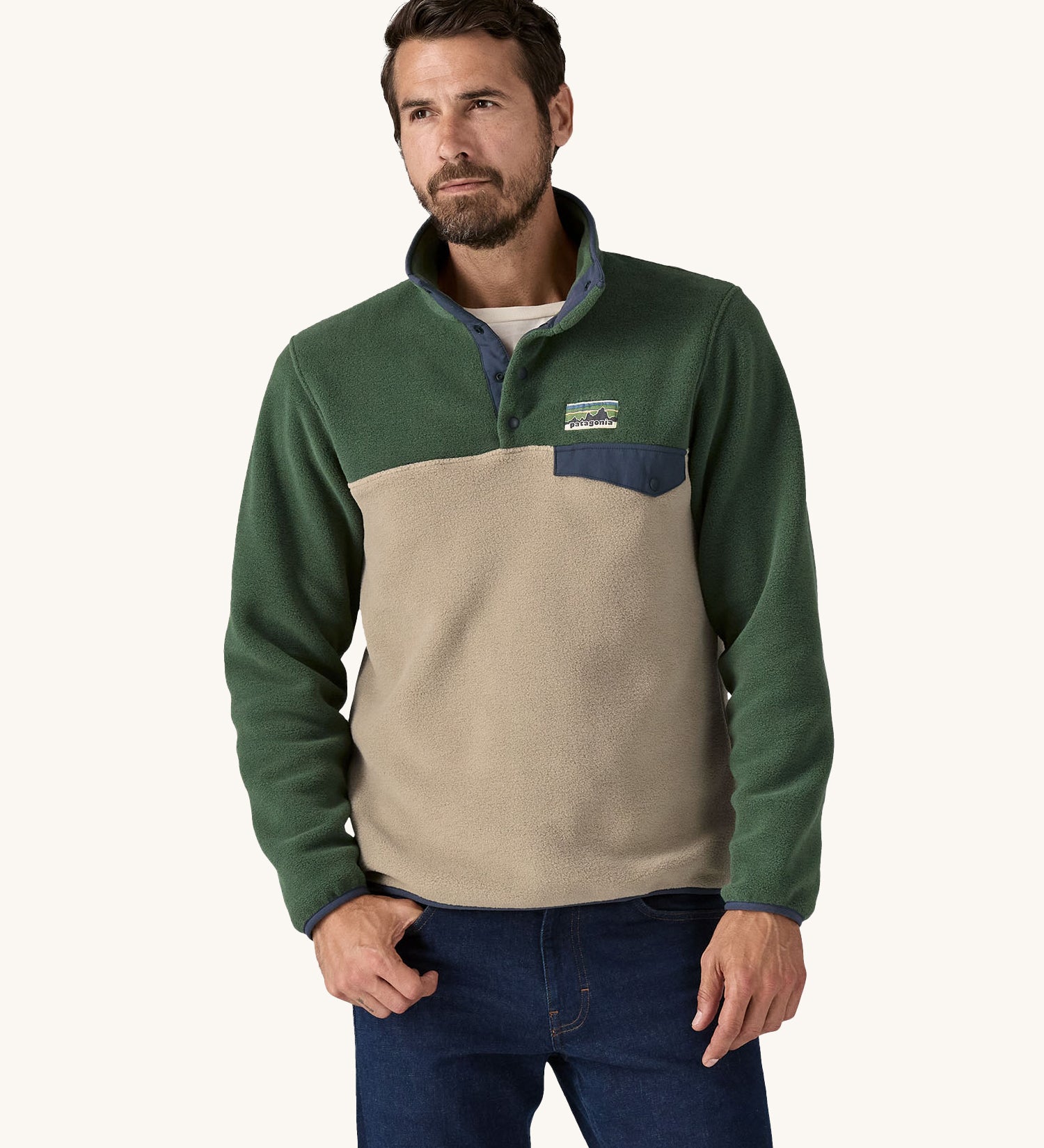 A man wearing a Patagonia Men's Lightweight Synchilla Snap-T Fleece in a Seabird Grey and green colour.  