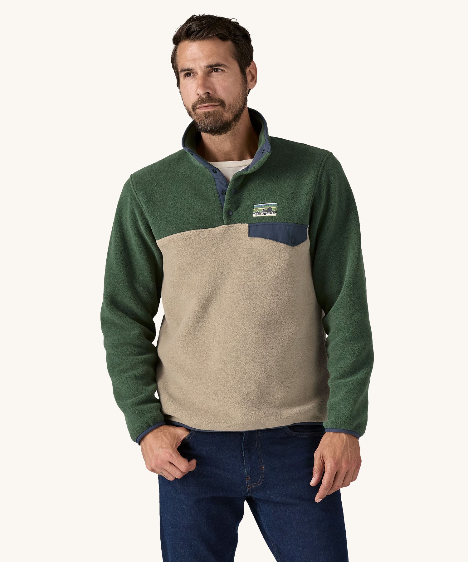 A man wearing a Patagonia Men's Lightweight Synchilla Snap-T Fleece in a Seabird Grey and green colour.  