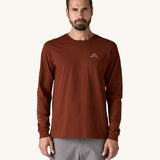 A man wearing a brown coloured Patagonia Men's Long Sleeved Organic T-Shirt with Driftways design. This t-shirt is a part of a wide range of Patagonia clothing and accessories available here at Babipur. 

