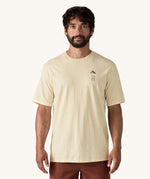 A man wearing a cream coloured Patagonia Men's Organic T-Shirt. This t-shirt is a part of a wide range of Patagonia clothing and accessories available here at Babipur. 