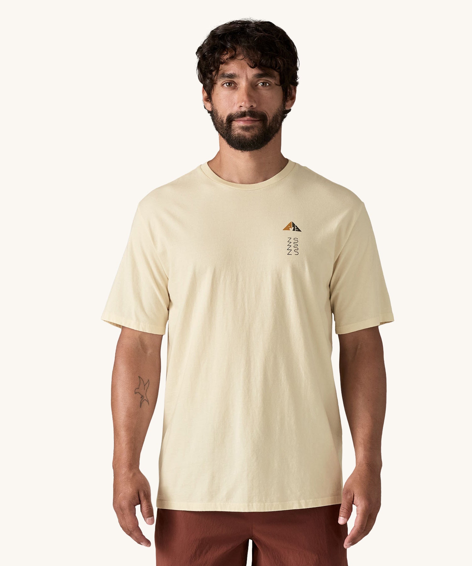 A man wearing a cream coloured Patagonia Men's Organic T-Shirt. This t-shirt is a part of a wide range of Patagonia clothing and accessories available here at Babipur. 