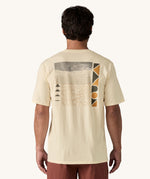 A view of the back of a man wearing a cream coloured Patagonia Men's Organic T-Shirt. This t-shirt is a part of a wide range of Patagonia clothing and accessories available here at Babipur. 