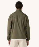 A man wearing the Patagonia Men's Outdoor Everyday Marsupial Pullover in Basin Green, facing away from the camera showing the back of the top.