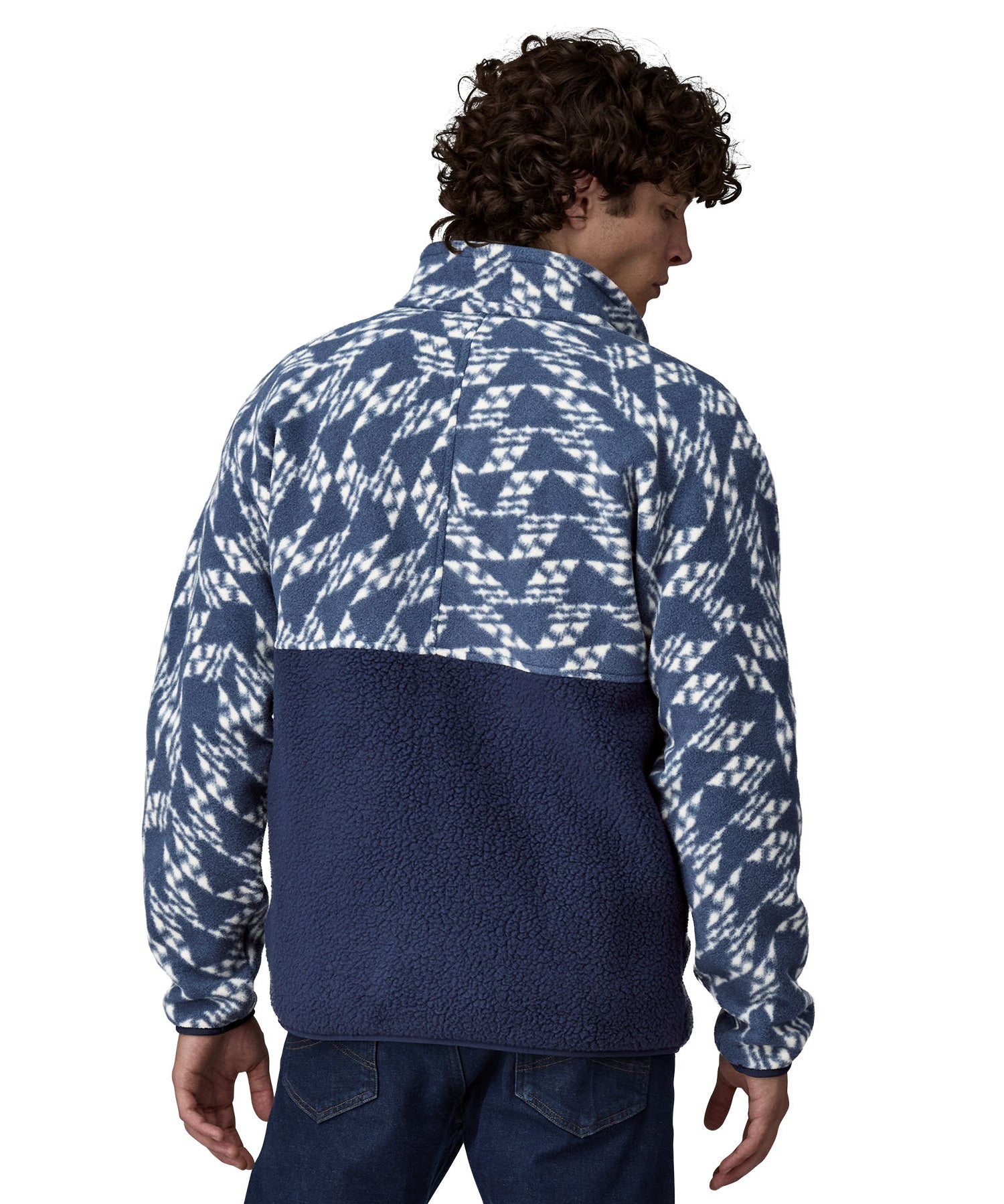 A man wearing a Patagonia Men's Retro Pile 1/2 Snap Pull Over in a New Navy design stood in front of a plain background. He is facing away from the camers showing the back of the pull over top. 