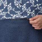 A close up of a hand unzipping the front pocket of a Patagonia Men's Retro Pile 1/2 Snap Pull Over in a New Navy design. 
