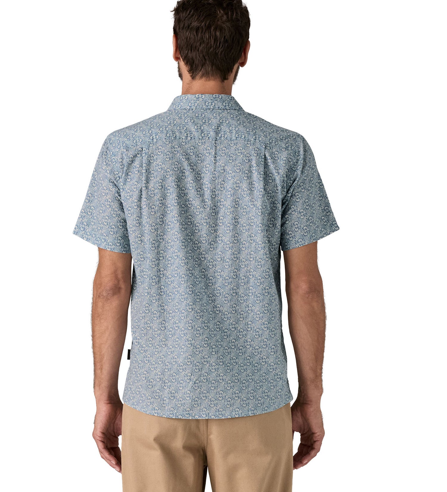 Back of man wearing the Patagonia Back Step Shirt, made with a blend of 55% industrial hemp and 45% organic cotton. In light blue with an understated Mountain Breeze print, it features short sleeves, and a subtle drop tail hem.  