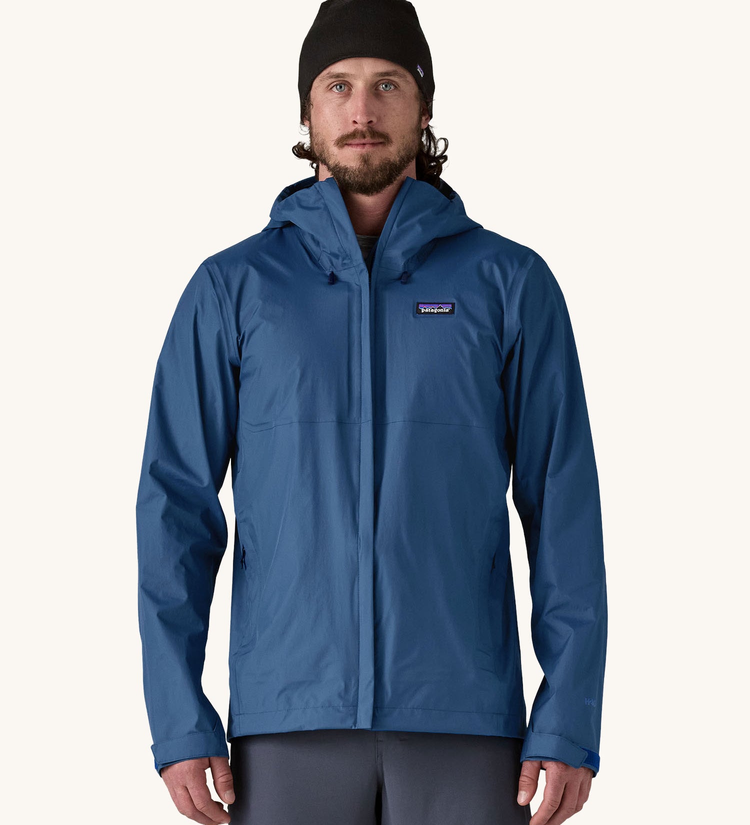 A man wearing the Patagonia Men's Torrentshell 3L Rain Jacket in a Clement Blue colour. We have a wide range of Patagonia adults and children's coats and clothing at Babipur. 