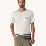 A man wearing the Patagonia Terravia Mini Bum Bag Hip Pack in a Smolder Blue colour on his waist.. 