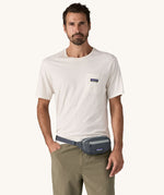 A man wearing the Patagonia Terravia Mini Bum Bag Hip Pack in a Smolder Blue colour on his waist.. 