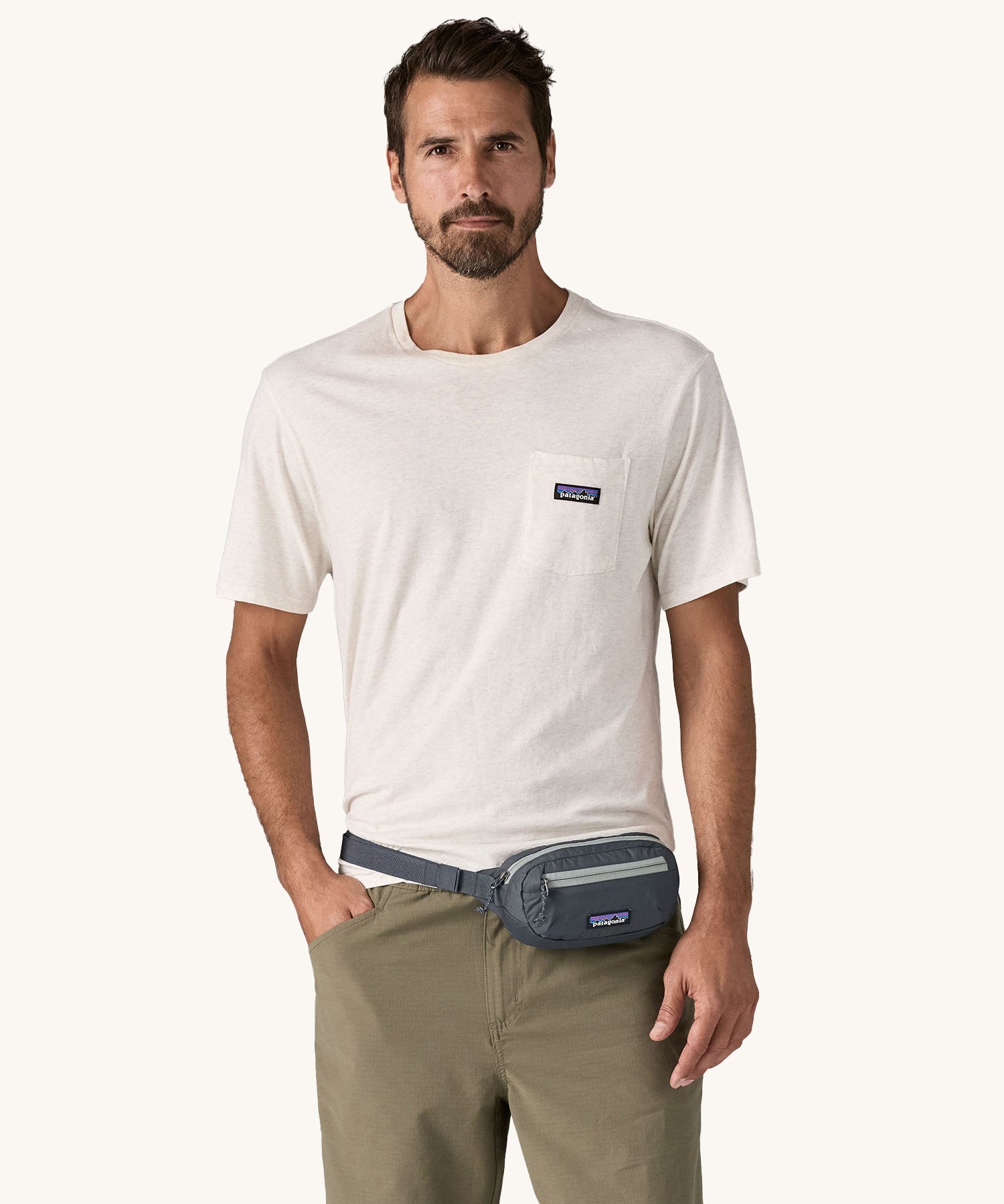 A man wearing the Patagonia Terravia Mini Bum Bag Hip Pack in a Smolder Blue colour on his waist.. 