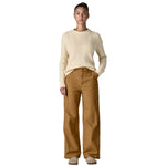 A woman wearing the Patagonia women's trousers available at Babipur. A wide leg style canvas trousers in nest brown colour, features a button fastener and 2 side pockets. 