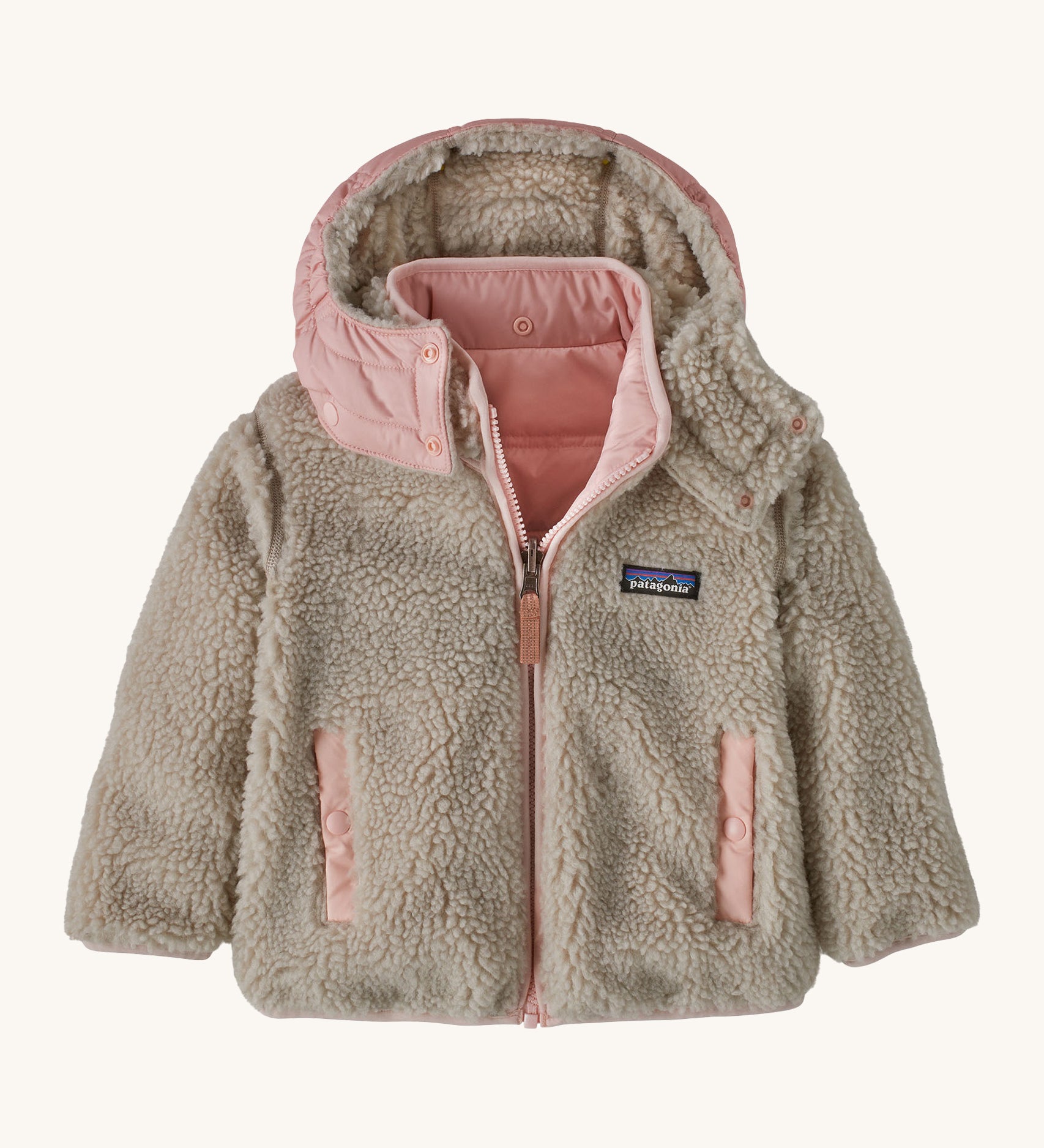 Patagonia little kids tribbles hoody. A reversible coat showing the natural fleece alternative side. Features a logo patch on the chest and 2 side pockets with popper fastenings