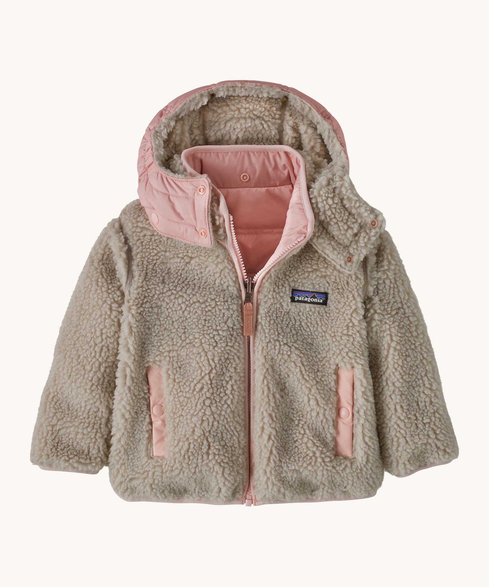 Patagonia little kids tribbles hoody. A reversible coat showing the natural fleece alternative side. Features a logo patch on the chest and 2 side pockets with popper fastenings