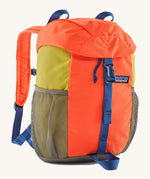 The Patagonia Kids Refugito 12L Backpack   , a vibrant orange backpack with block mustard colour side panels. Features 2 side mesh pockets in grey and a blue buckle to close the lid. Logo patch is stitched on the front panel.