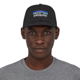 A front profile image of a man wearing the Patagonia P-6 Logo Trucker Hat in a Black colour