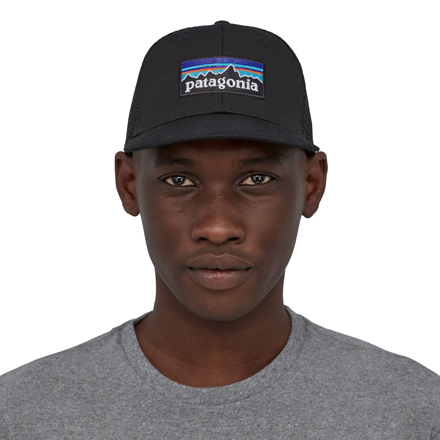 A front profile image of a man wearing the Patagonia P-6 Logo Trucker Hat in a Black colour