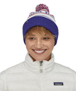 An adult wearing the Patagonia park stripe viking blue. Features a red, white and blue pom pom pom and blue turn up ribbed brim
