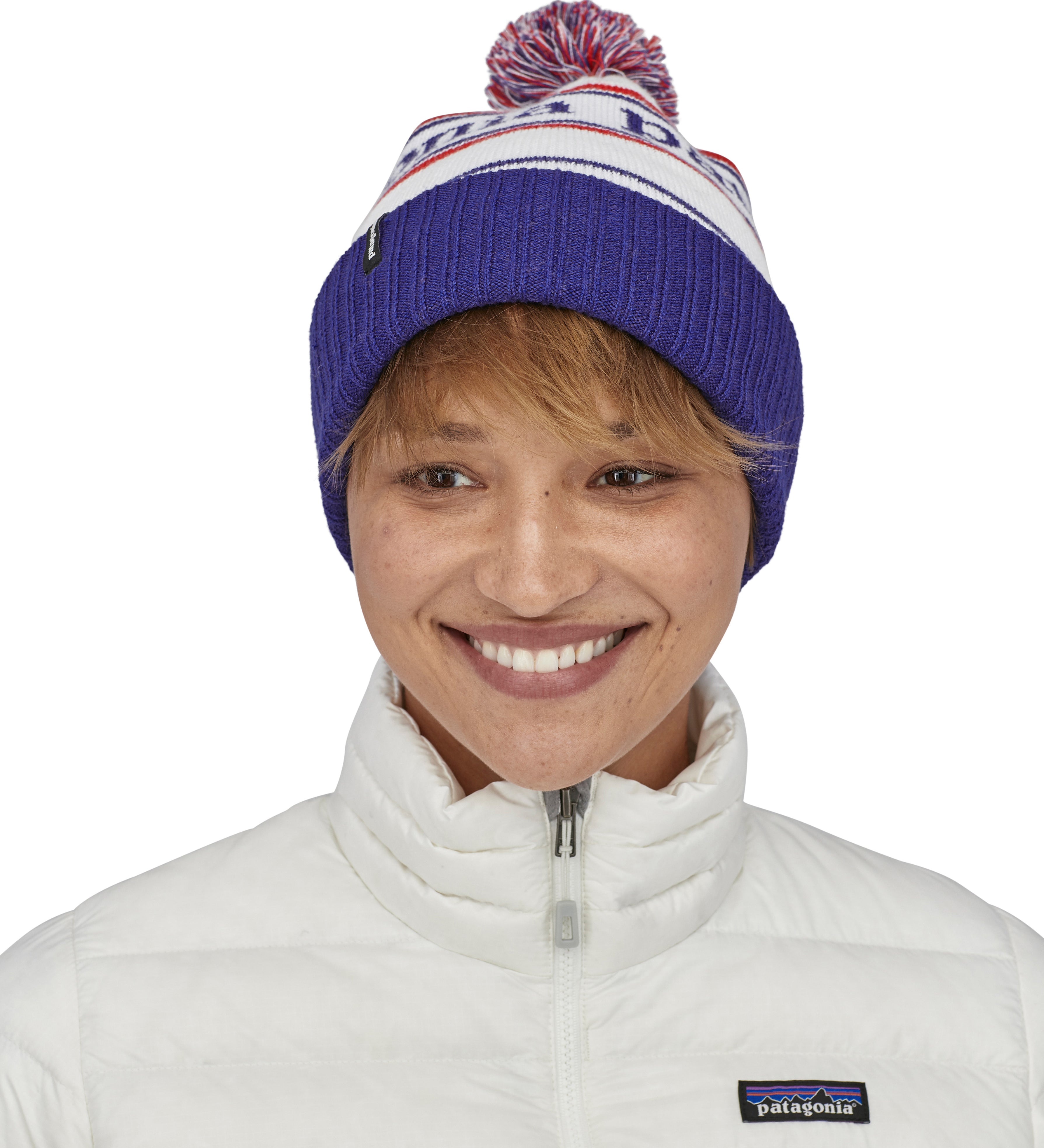 An adult wearing the Patagonia park stripe viking blue. Features a red, white and blue pom pom pom and blue turn up ribbed brim