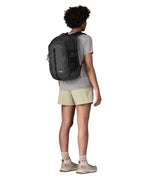 Woman wearing the Patagonia 26L refugio backpack in black with matching straps and top handle.