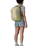 Person wearing the Patagonia 26L refugio backpack in stone with grey straps and top handle.