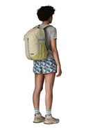 Person wearing the Patagonia 26L refugio backpack in stone with grey straps and top handle.