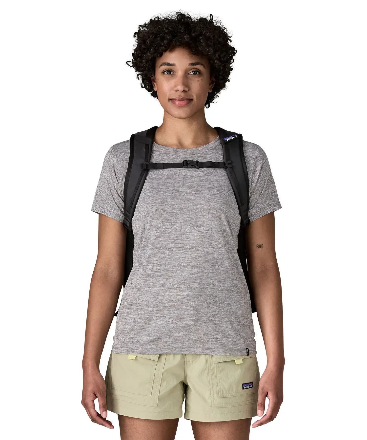 Woman wearing the Patagonia's 26L refugio backpack in black with matching chest strap and quick release buckle.