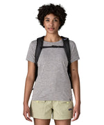 Woman wearing the Patagonia's 26L refugio backpack in black with matching chest strap and quick release buckle.