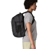Side of woman wearing the Patagonia's 26L refugio backpack in black with matching chest strap and buckles