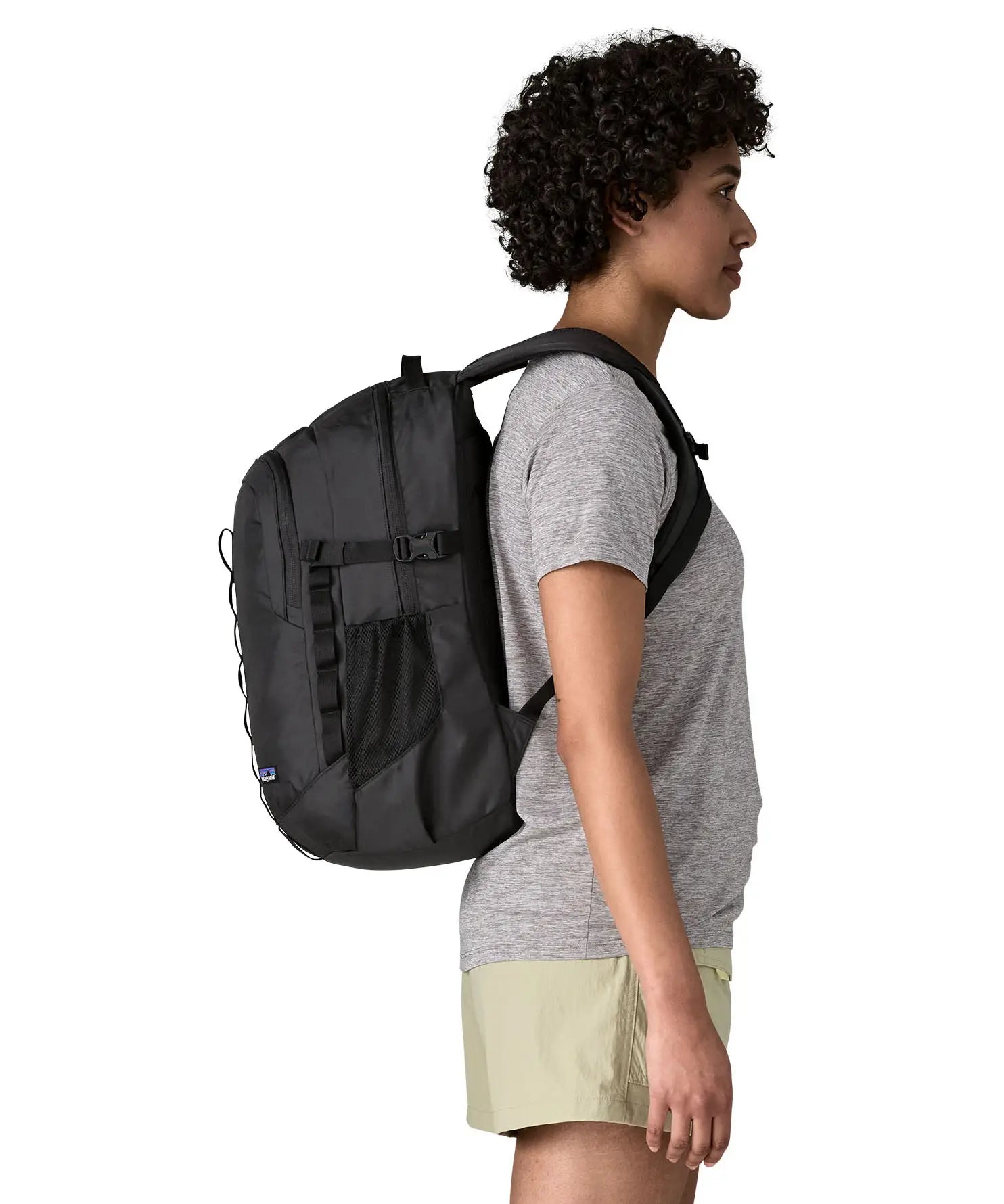 Side of woman wearing the Patagonia's 26L refugio backpack in black with matching chest strap and buckles