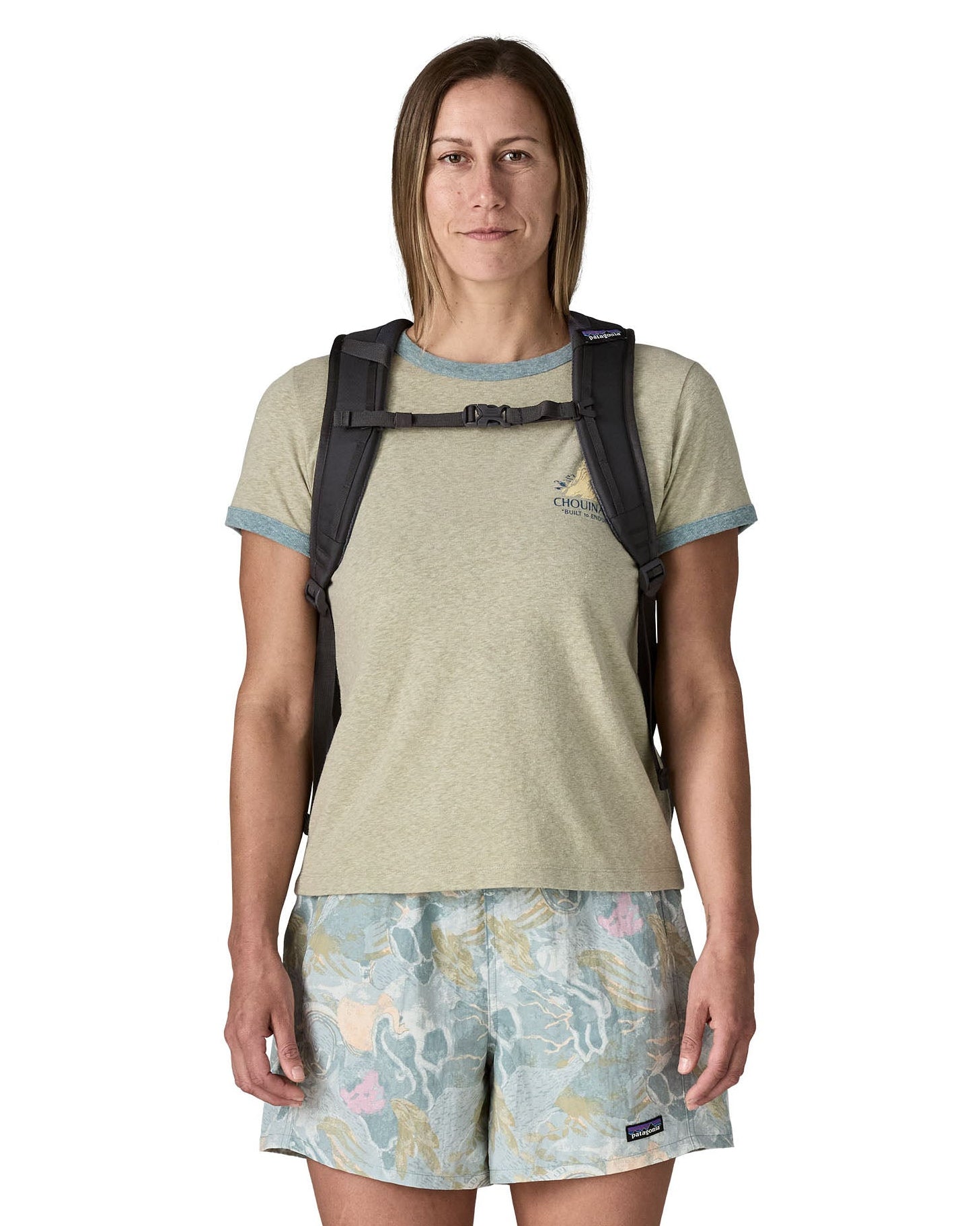 Woman wearing the Patagonia's 26L refugio backpack in dark blue with matching chest strap and quick release buckle.