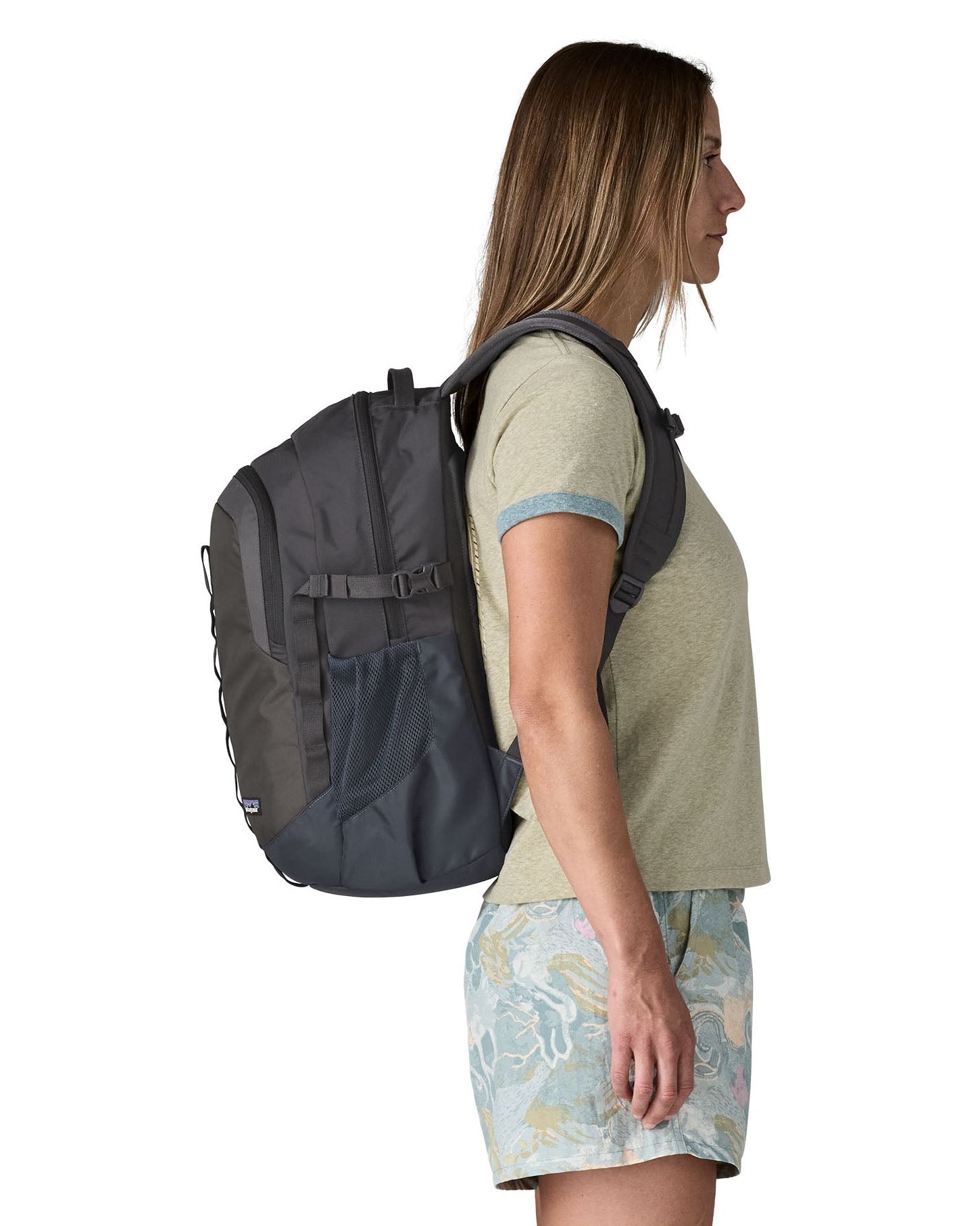 Side of woman wearing the Patagonia's 26L refugio backpack in dark blue with matching chest strap and buckles