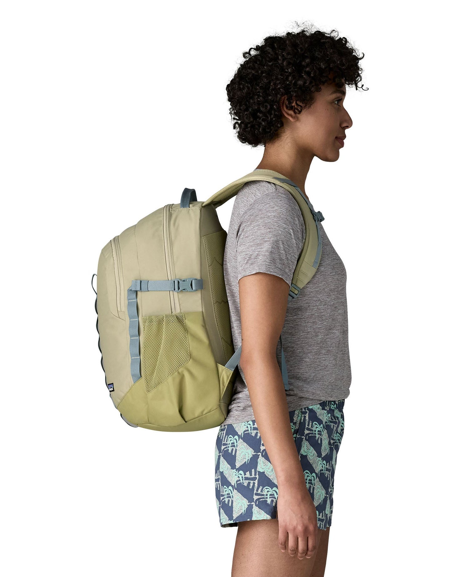 Side view of person wearing the Patagonia 26L refugio backpack in stone with grey chest strap.
